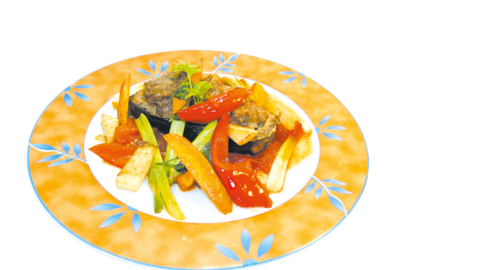 Auf einem verzierten Teller servierte gefüllte Auberginen mit Hackfleisch und gebratenem Gemüse 