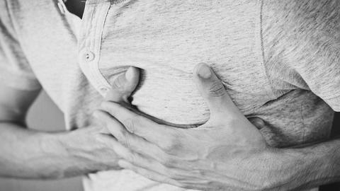 Mann fasst sich an die Brust und hat Schmerzen