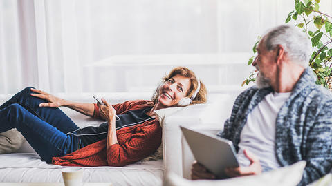 Ehepaar liegt auf dem Sofa rum und hört Musik