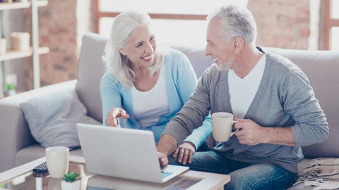 Zwei Menschen sitzen vor dem Computer und lächeln