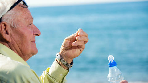 Mann nimmt im SOmmer sein Medikament ein