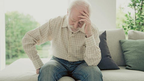 Mann sitzt erschöpft auf dem Sofa 