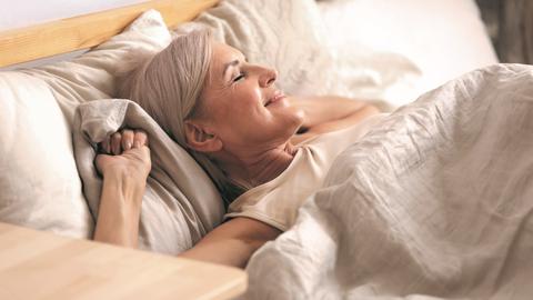 Frau wacht gut erholt vom Schlafen auf