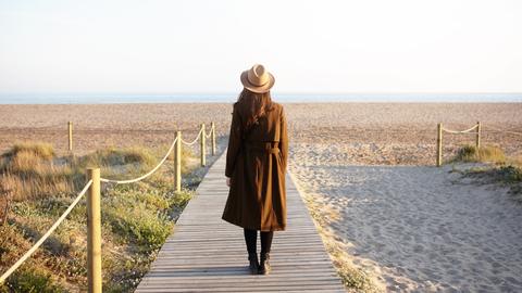 modische Frau schaut mit dem Rücken zum Strand