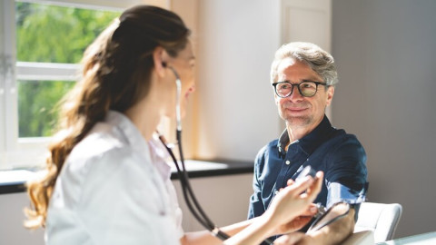 Ärztin misst beim Herrn den Blutdruck und führt einen Check-Up durch